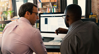 Image of two people looking at a computer working together