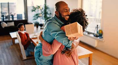 Image of a man and woman hugging with a gift in their hands