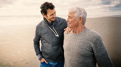 Image of two people standing and smiling on a beach