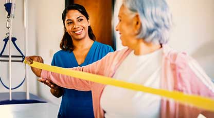 Image of a physical therapist assisting an older woman exercise