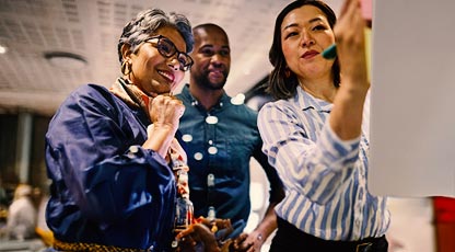 Image of three people looking at something together in the office 