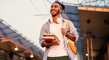 Student walking with headphones and carrying books