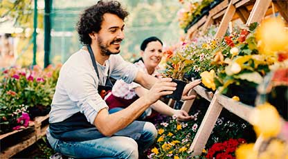 A person smiles while looking at plants