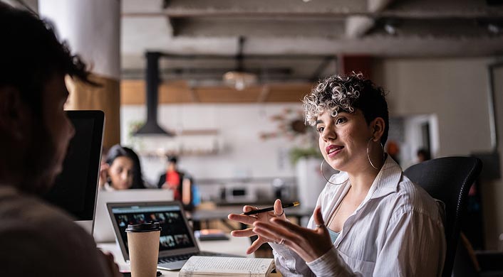 Image of person talking to a peer in office setting