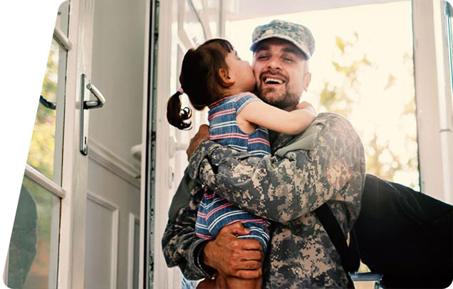 Service memeber holding a child and smiling