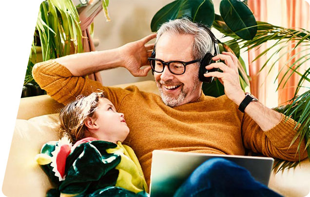A parent with headphones on smiles at their young child