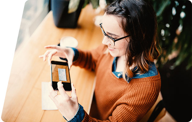 Image of a person making a mobile deposit with their smartphone camera in a coffeeshop