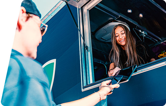 Person making a mobile payment at a food truck by tapping their smarphone on the vendor's tablet computer