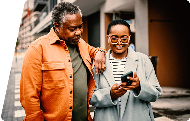 Image of a young person showing their smartphone screen to an older person who has a hand placed on the young person's shoulder