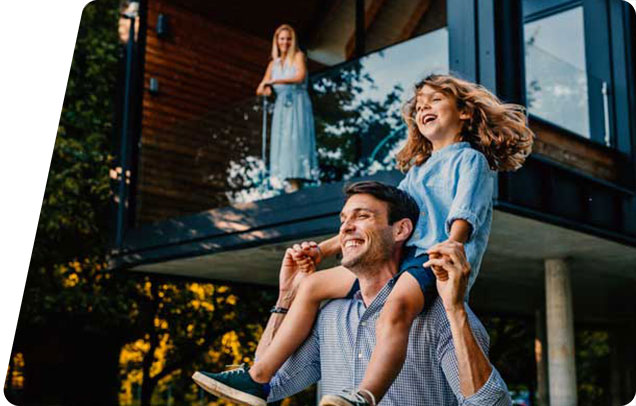 Parent with kid on shoulders smiling with other parent watching from deck
