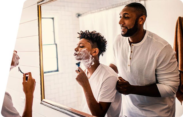 A parent teaches their child how to shave in a bright bathroom