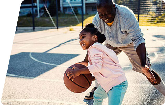 A parent and young child playing basketball outside
