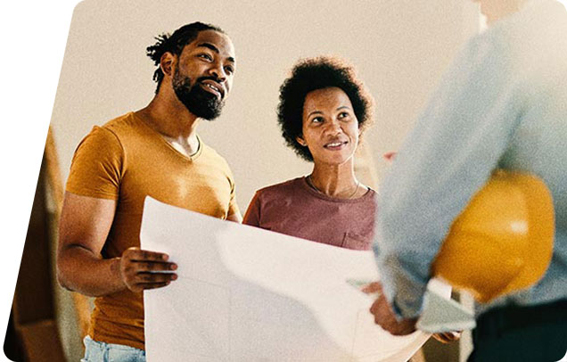 A couple reviews blueprints while speaking with a construction worker