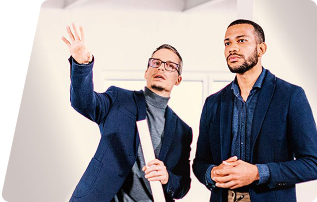 An architect with blueprints in hand explains their vision to a client