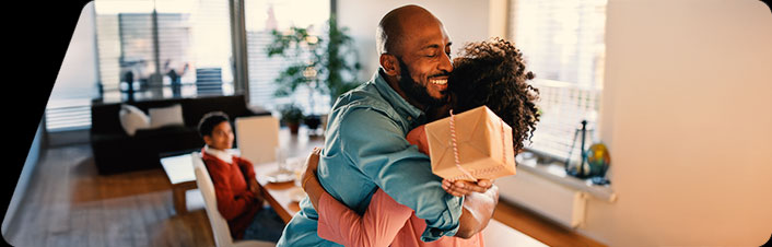 Image of a man and woman hugging with a gift in their hands