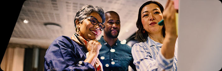 Image of three people looking at something together in the office 