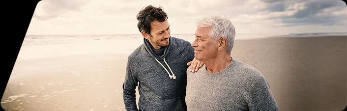 Image of two people standing and smiling on a beach