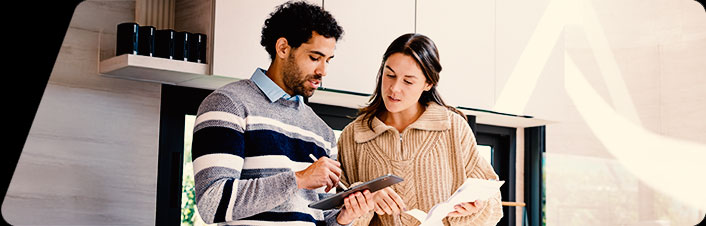 Image of a woman and man looking at a document and calculating costs together in a new house