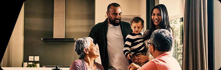 A family of six gathers in a bright, modern kitchen, enjoying a warm moment together.