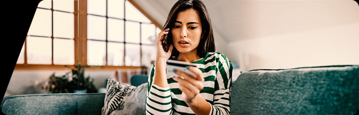 Image of a woman on the phone looking at credit card