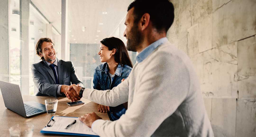 People sitting around a desk and shaking hands