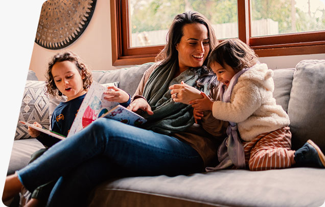 An adult sits on a couch with two children, sharing a warm moment together.