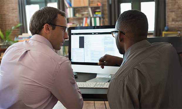 Image of two people at a desk looking at a computer