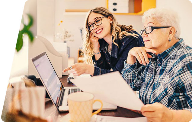 A younger person helping an older person use the computer