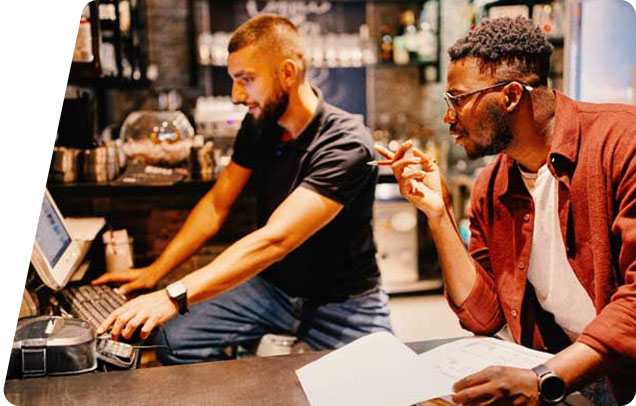 Two people working on a computer in a restaurant