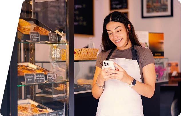 Person with apron in bakery using phone